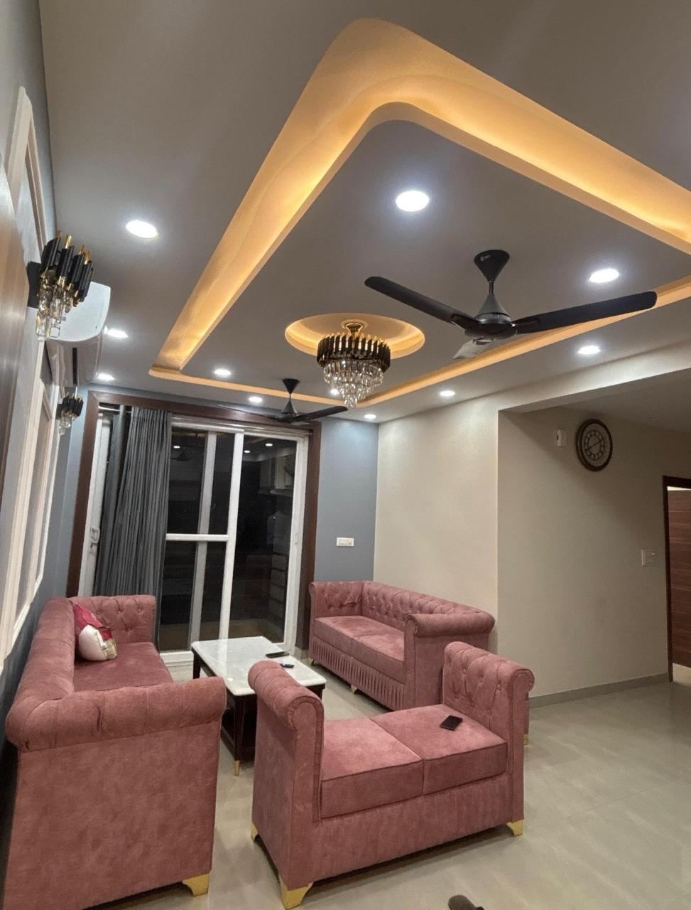 Modern residential drawing room with pink chesterfield sofas and gold chandelier